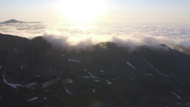 Aerial Peruvian Andes mountain peaks rise above clouds with rugged ridges and high altitude drama. Misty layers, vapor flow, elevated relief create striking atmospheric scenery across remote ranges.