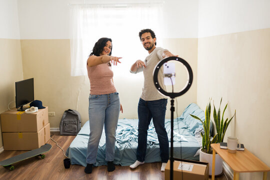 Happy couple vloggers dancing and making a video for followers, celebrating their poor but happy life in a new home