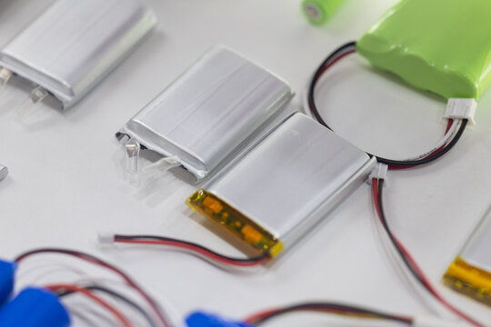 Silver lithium polymer battery packs with connecting wires on white. Compact energy solutions for small portable electronics. Lightweight rechargeable cells for modern gadgets