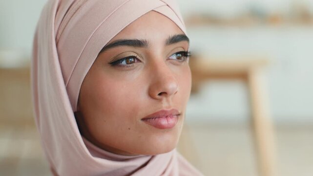 Close up pensive Muslim woman in pink hijab looking away thinking solution indoors serious calm expression Arabian female Islamic girl portrait Eastern ethnicity dreaming contemplating idea lifestyle