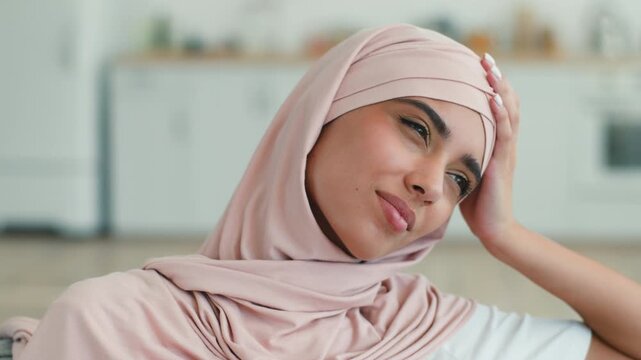 Ill Muslim woman in hijab holding head headache pain at home indoor sad female suffering migraine sick unhealthy girl Arabian feeling bad pressure blood health problem medicine treatment tired fatigue