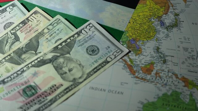 US dollar banknotes are spread across a world map with a national flag.