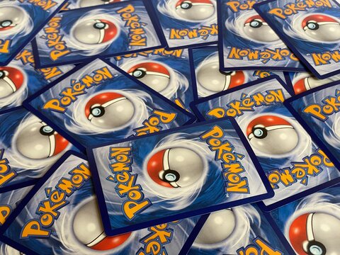 Bekasi, Indonesia - March 04, 2026: A close-up, high-angle view of multiple Pok&eacute;mon Trading Card Game (TCG) cards scattered on a surface, showing the iconic blue back design with the Pok&eacute; Ball and yel