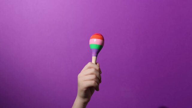 Child with toy maraca on purple background, closeup