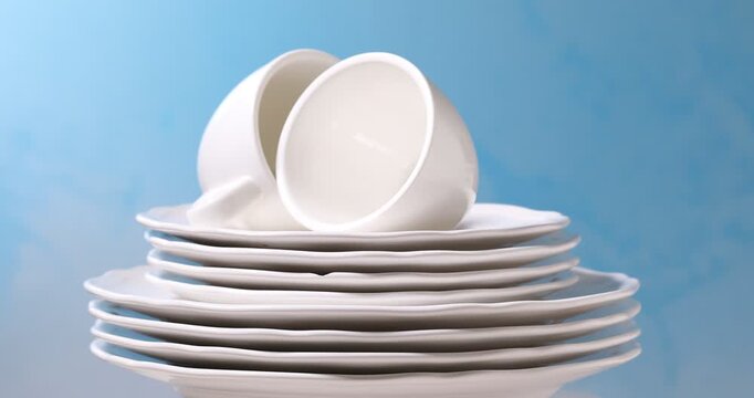 Clean dishes spinning against light blue background, closeup