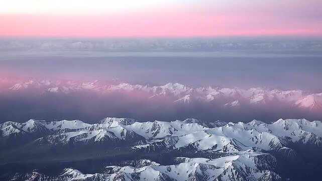 Aerial Andes scene shows ice covered summits, pink cloud layer, golden sunset rays. Airplane window frames Andean cordillera, snowcapped ridges under rose haze during twilight flight.