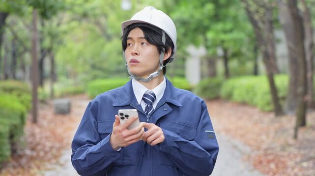 携帯を持つ作業着を着た男性