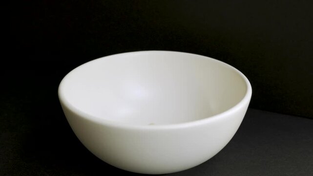 Empty_white_bowl_filling_with_white_beans_on_black_background_4k_10bit_120fps