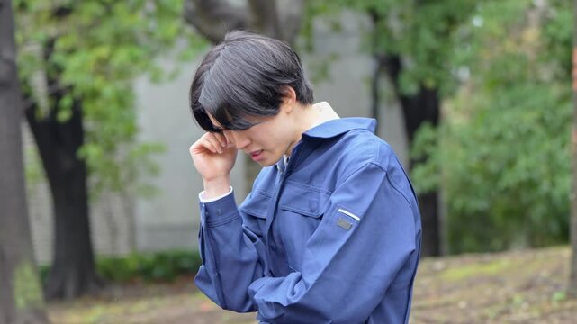 悩む作業着を着た男性