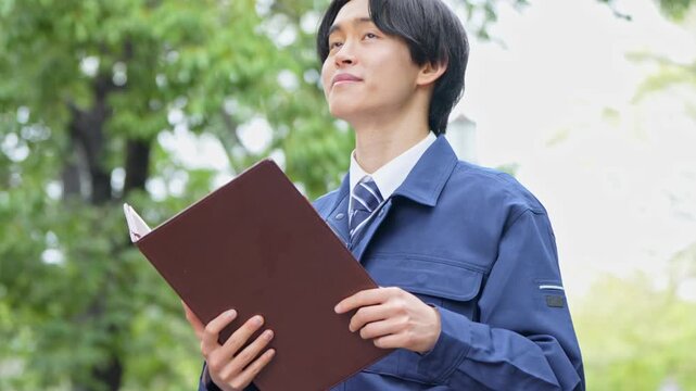 ファイルを持つ作業着を着た男性