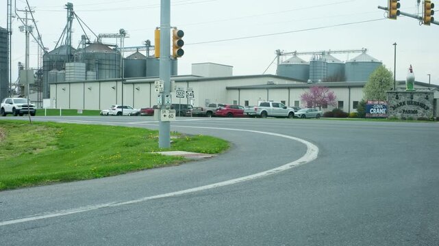 Traffic flowing through a rural intersection with large industrial farm silos