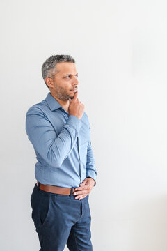 Pensive mature man holding hand on chin looking away in deep thought