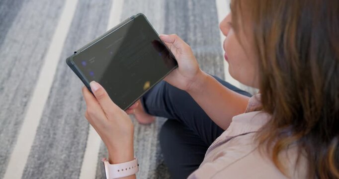 African American woman holding tablet on striped rug, tapping left screen, reading, copy space