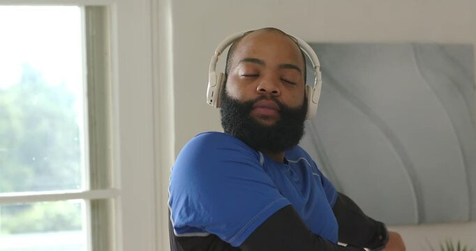At home African American man hearing cue via white headset blue shirt opening eyes to window