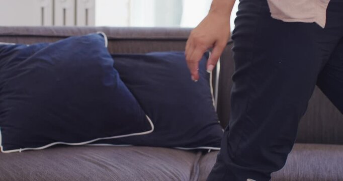 Adult woman adjusting blue BP cuff, monitor on sofa, finishing check, leaving phone, copy space