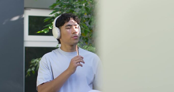 Pale panel sliding away, man wearing headset listening, tapping pencil, jotting notes for education