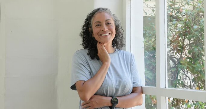 Closing eyes African American woman turning to camera tucking hair smiling with lapel-mic by window