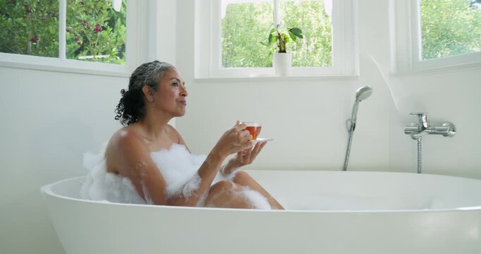 Woman lifting teacup and sipping in tub, gazing windows, animated leaf circling tub for wellness