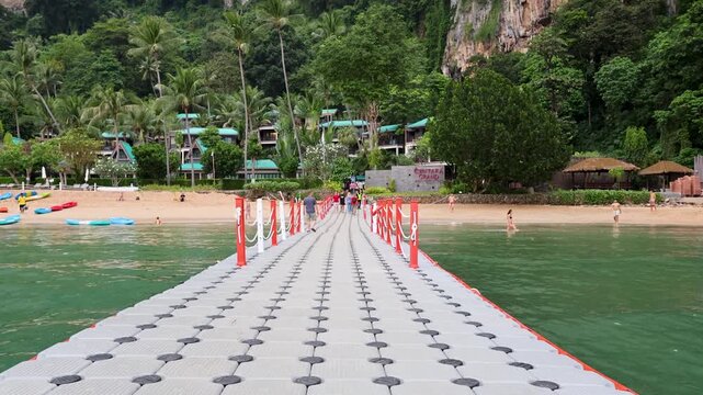 Floating plastic pier leading towards tropical beach resort in Thailand.