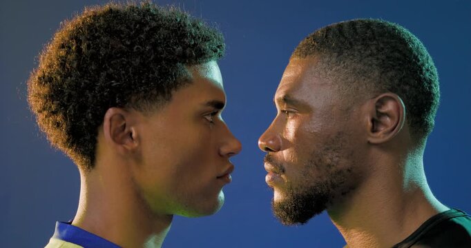 African men entering frame opposite sides, holding gaze, preparing pregame in studio with jerseys