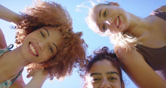 Vertical video: Diverse female friends spotting low phone, leaning, laughing, filming in swimwear