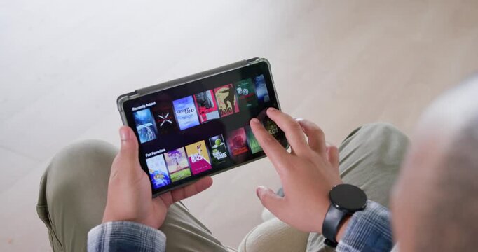 African American man holding tablet right hand tapping, swiping media while browsing in living room