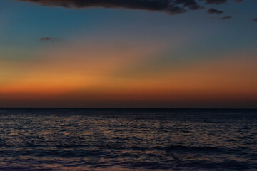 Fototapeta premium Beach scene at dusk, glowing horizon, and textured evening clouds