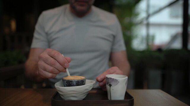 Man Tasting Vietnamese Egg Coffee With Spoon, Close Sensory Sip, Creamy Custard Foam Lifted From Bowl, Porcelain Cup With Black Coffee Beside Bowl, Indoor Cafe Table, Candid Food Review
