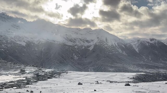 NYINGCHI, TIBET/CHINA - APRIL 13, 2026: Divine rays of light sweeping across a snow-covered Tibetan mountain village during a winter morning in Nyingchi.