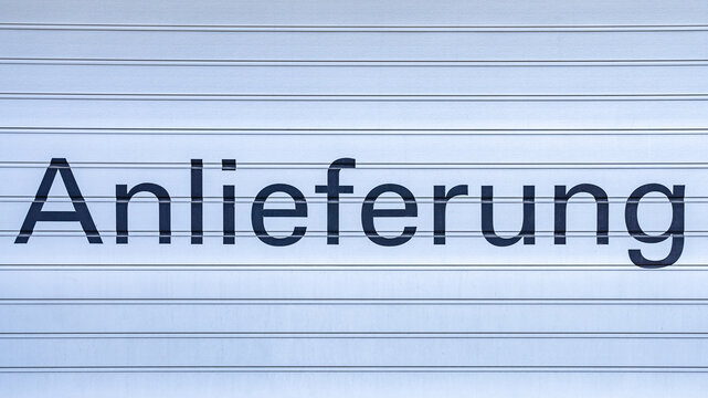 Schriftzug &bdquo;Anlieferung&ldquo; auf einem Industrietor, Symbolbild f&uuml;r Logistik, Warenannahme und Lieferverkehr. Tor mit deutscher Schrift, Lieferung.