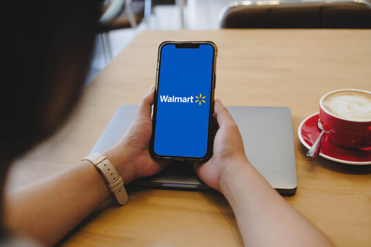 Bangkok, Thailand. April 16, 2026; An over the shoulder view of a person holding a smartphone horizontally displaying the Walmart company logo on the screen.