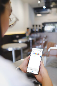 Bangkok, Thailand. April 11, 2026; An over the shoulder view of a person holding a smartphone that displays the Google search engine homepage on the screen.