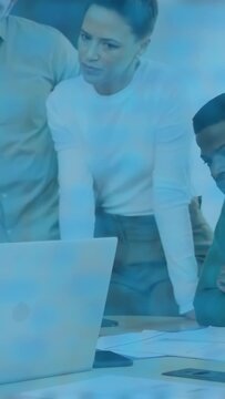 Vertical video: Lead woman leaning forward, animating tags over laptop docs phone for office review