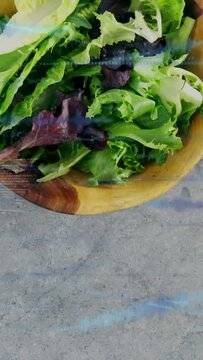 Vertical video: Camera moving down showing wood bowl of greens on stone lines guiding food creators