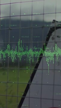 Camera moving right revealing fence and sign, translucent green waveform animating wind farm data
