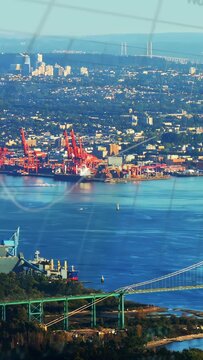 Vertical video: Drone panning coastal port and city, revealing bridge, cranes, ship, for shipping