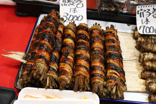 Grilled eel wrapped around burdock root at a food market.