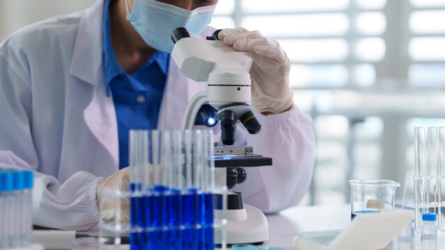 Asian adult scientist uses microscope conducting laboratory research experiment medical discovery healthcare innovation technology development science professional work