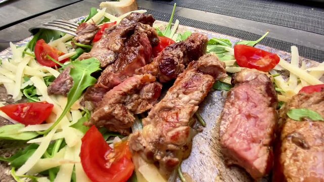  Sliced Medium-Rare Steak Tagliata with Arugula, Parmesan, and Tomatoes