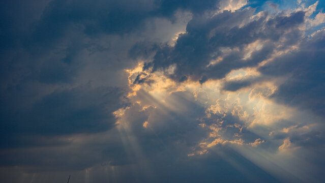 A serene cloudy sky with sun rays peeking through the clouds