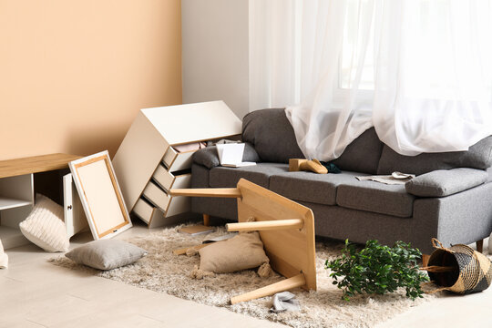Interior of light living room with messed furniture after earthquake