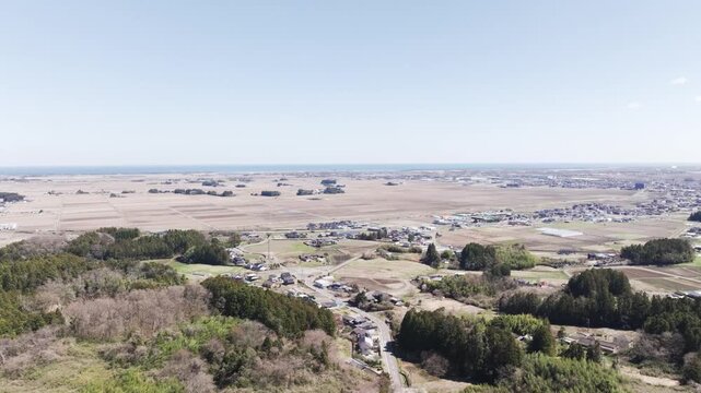Aerial drone rising view from mountains to Sendai plain and Pacific Ocean in Japan, wide landscape transition