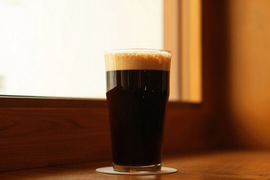 Dark beverage fills tall glass with frothy top.