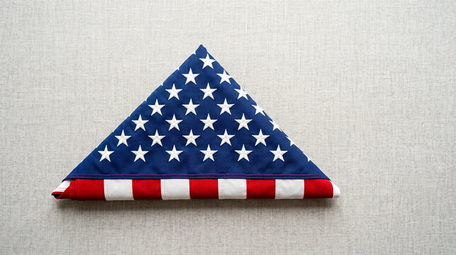 Folded American flag triangle on neutral fabric background