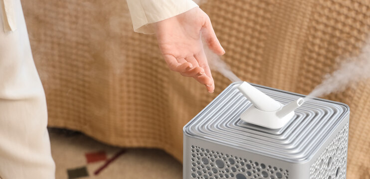 Woman with modern air humidifier in bedroom, closeup
