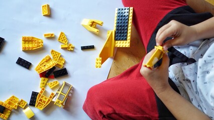 Fototapeta premium Close up of child's hands playing with colorful plastic bricks or lego. Toddler having fun and building out of bright constructor bricks. Development toys