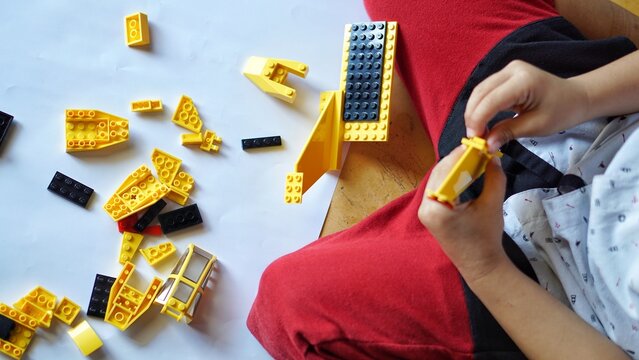 Close up of child's hands playing with colorful plastic bricks or lego. Toddler having fun and building out of bright constructor bricks. Development toys