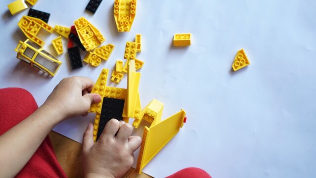 Close up of child's hands playing with colorful plastic bricks or lego. Toddler having fun and building out of bright constructor bricks. Development toys