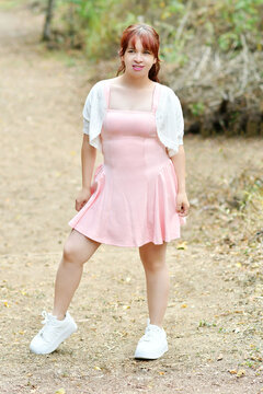 Mujer latina con un vestido rosa, posando para la c&aacute;mara mientras esta en un parque ecol&oacute;gico al aire libre.