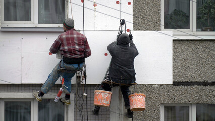 Naklejka premium climbers work on the building, climbers are working on the insulation of facades of a multi-storey residential building